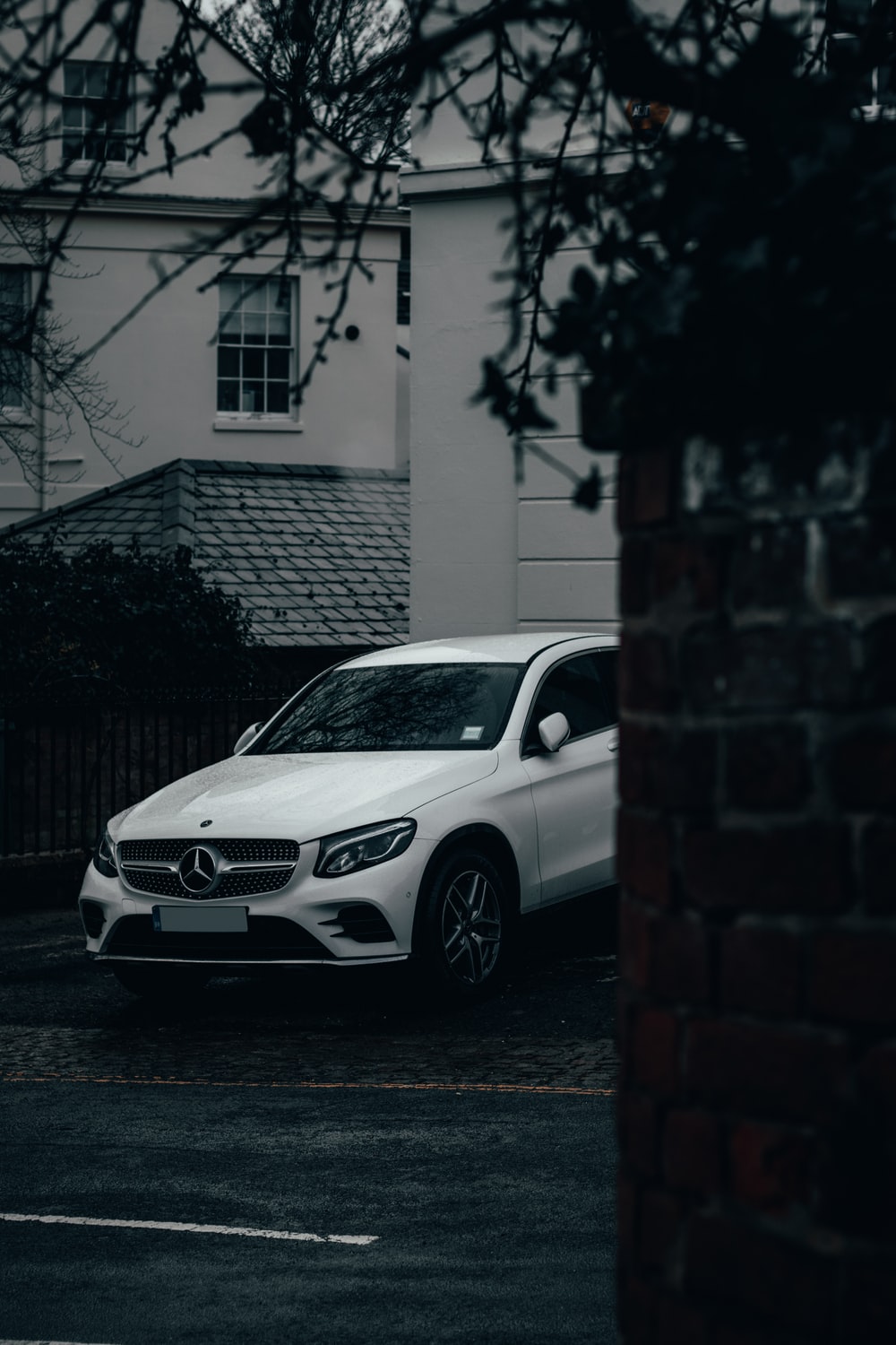 white mercedes benz c class parked beside brick wall photo