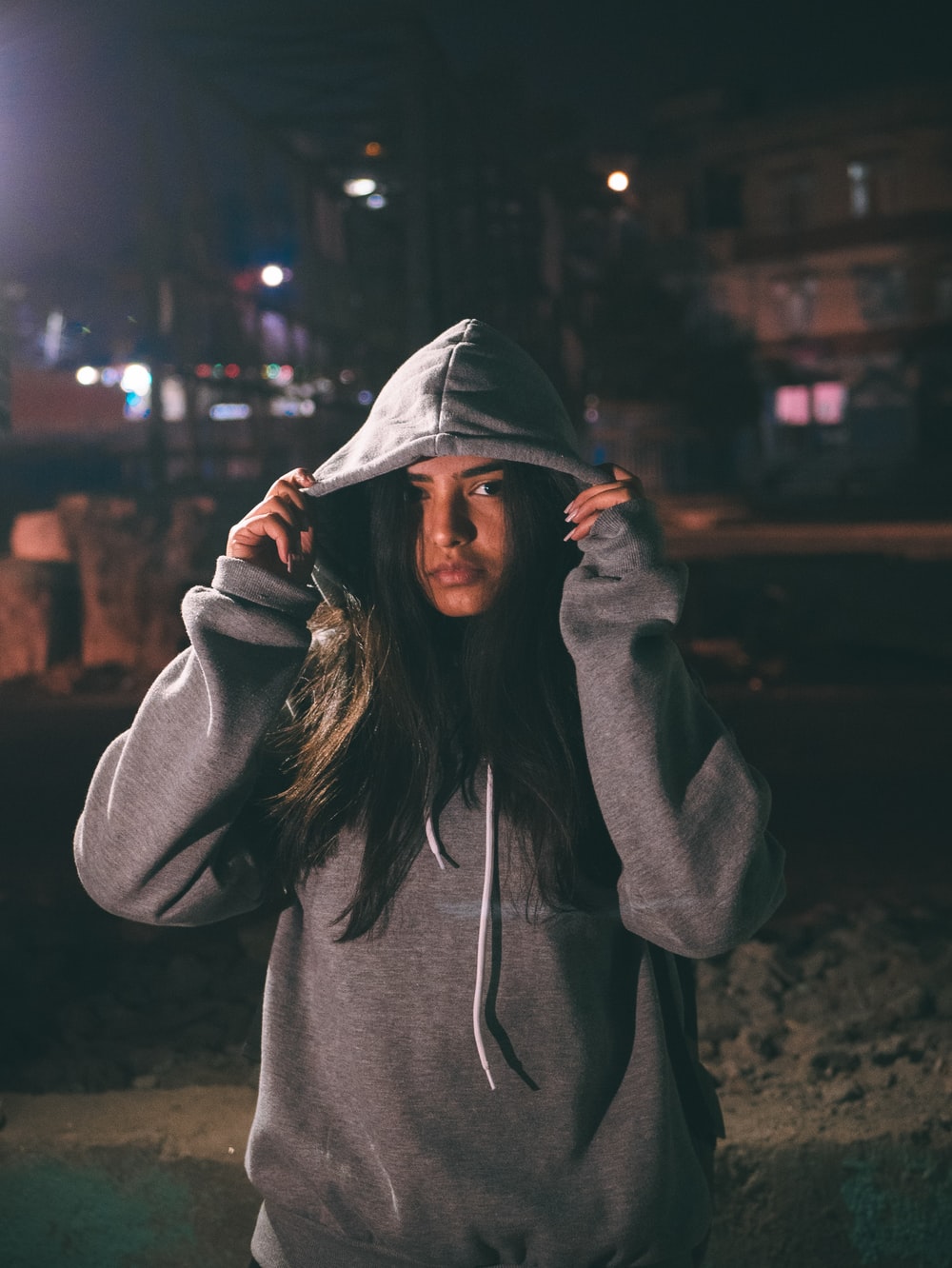 woman in hoodie while both hands holding the hood photo