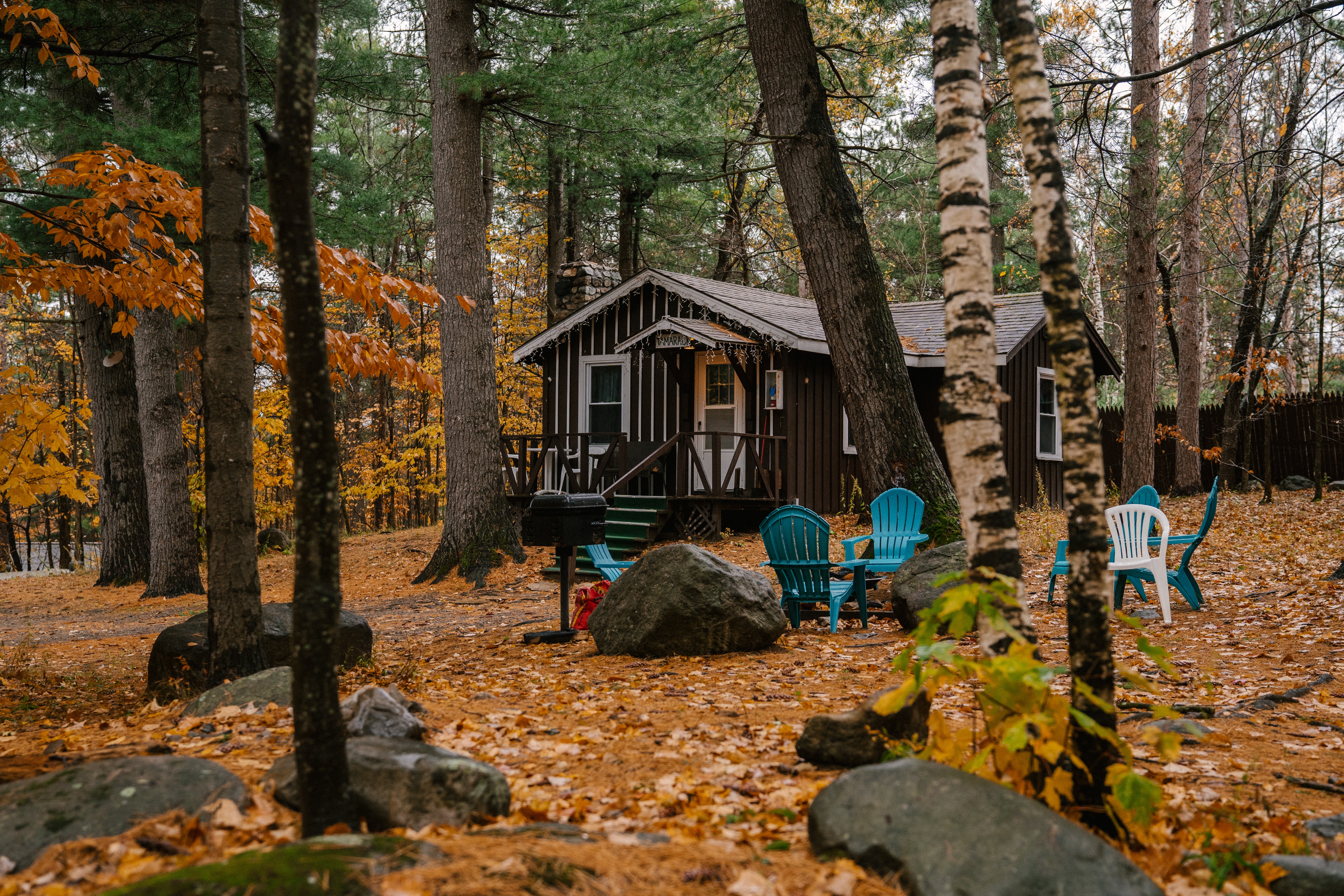 Cozy wooden house and chairs in autumn forest · Free