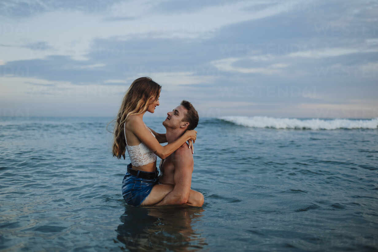 Boyfriend carrying girlfriend while standing in water at beach