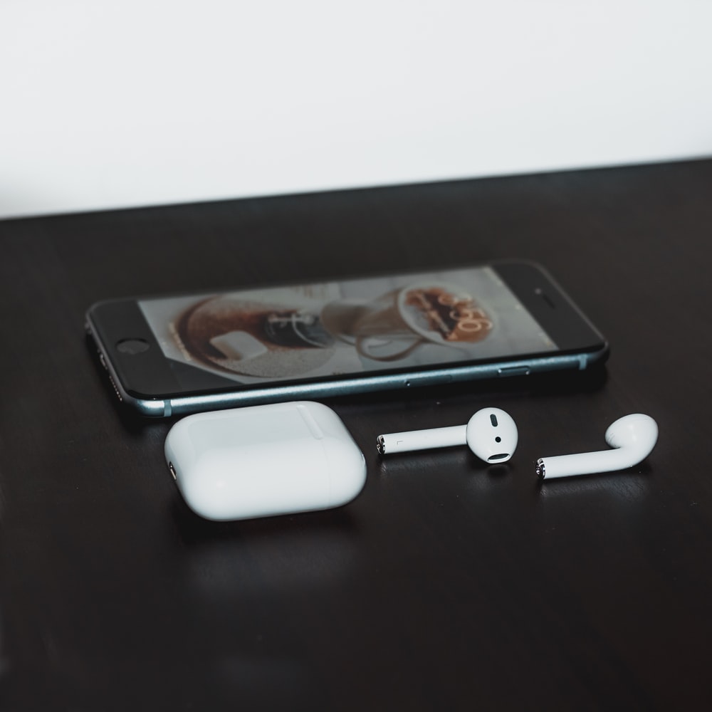 space gray iPhone 6 and Apple AirPods with case on black wooden table photo