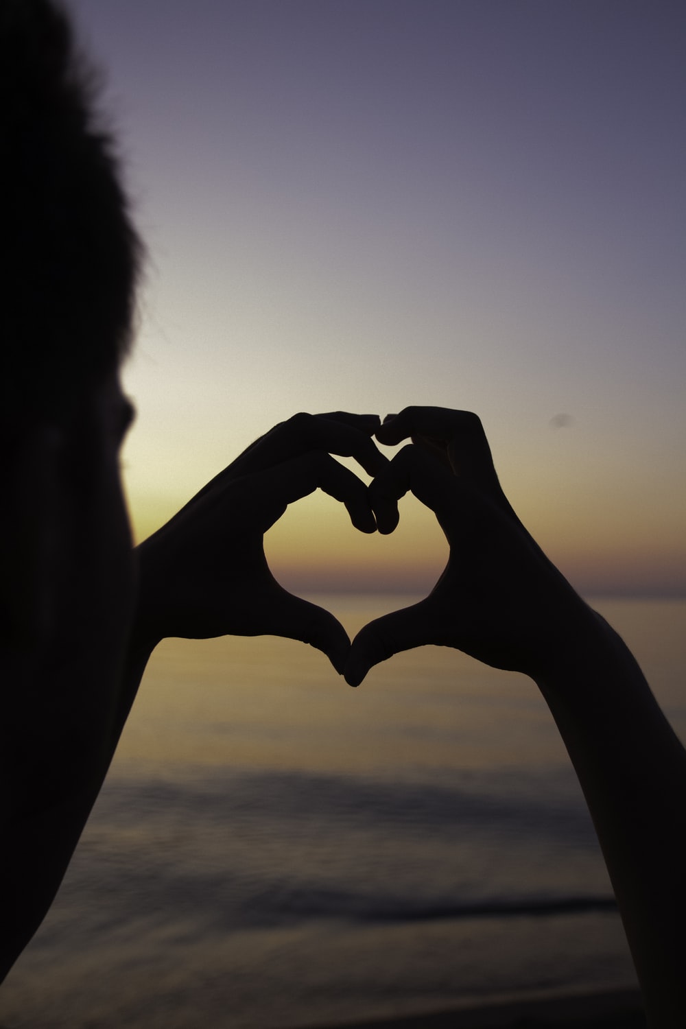 silhouette of person doing heart handsign photo