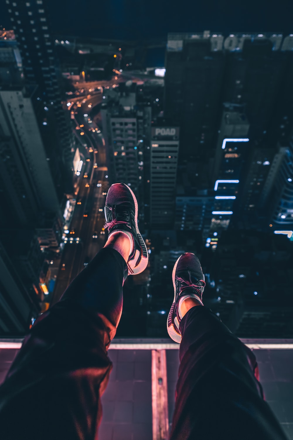 person sits at the edge of building photo